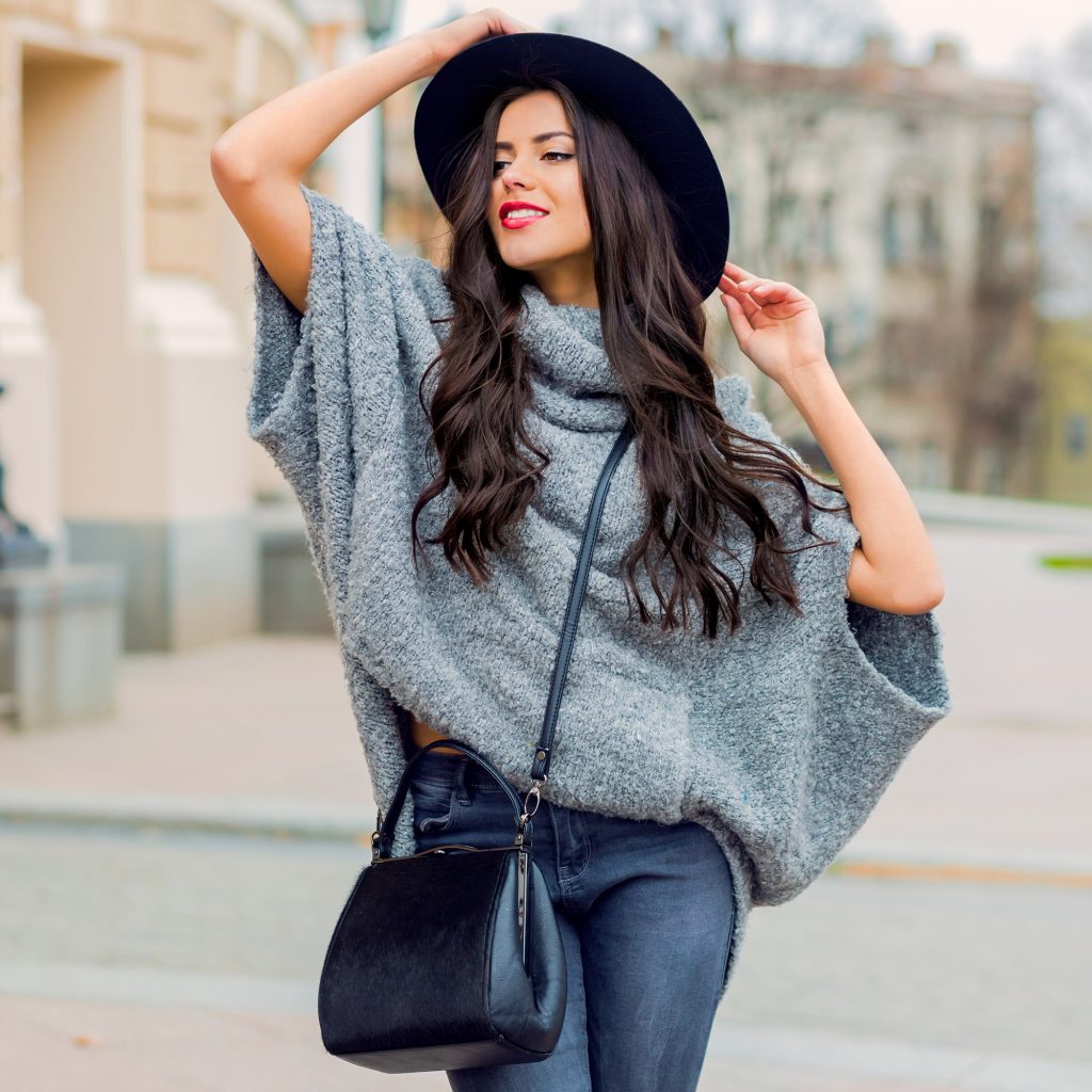 retrato de moda al aire libre de glamour sensual elegante joven vistiendo ropa de otono sombrero negro sueter gris y bolso de cuero labios rojos brillantes ciudad vieja de fondo